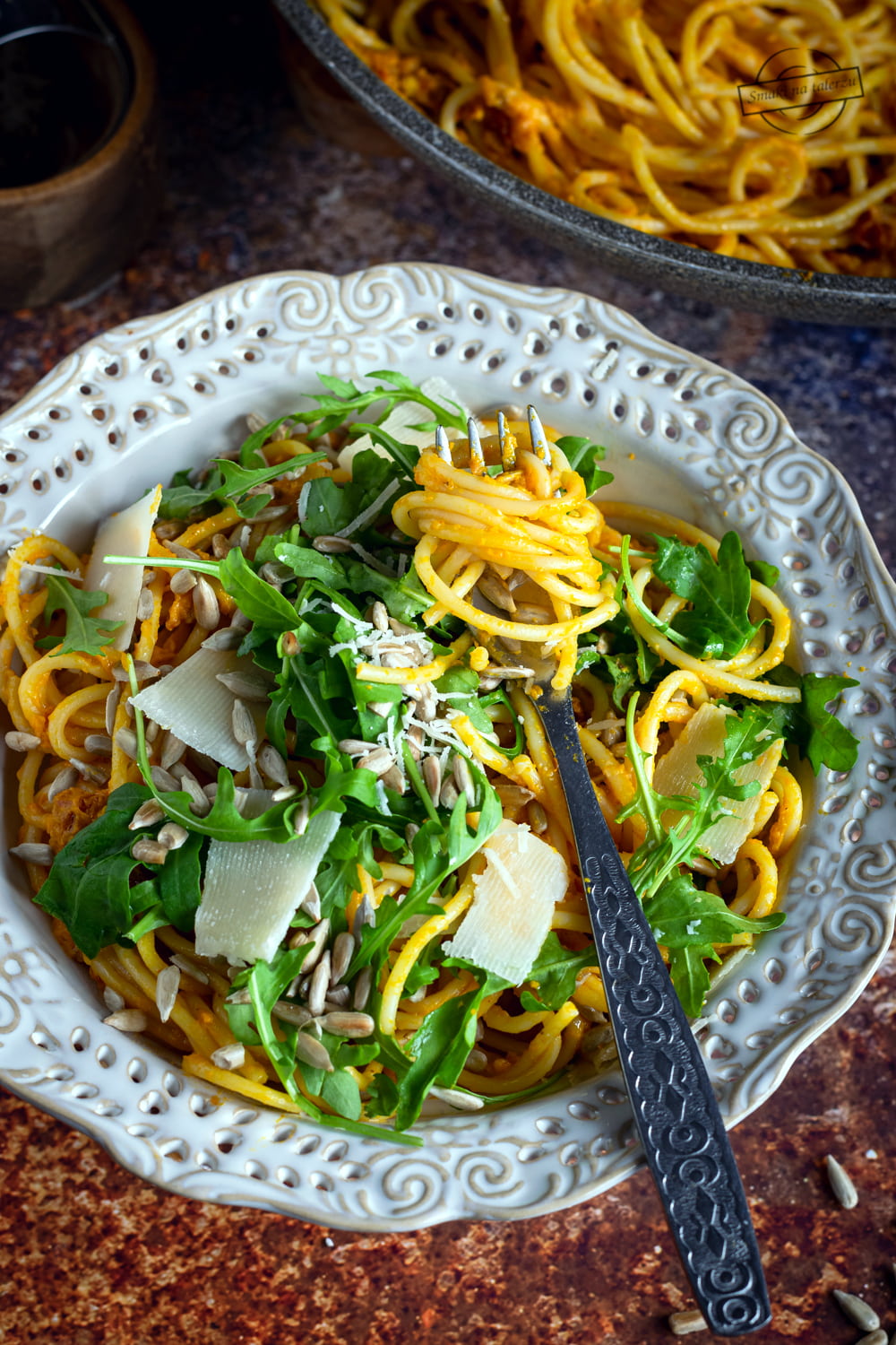 Spaghetti z sosem dyniowym, rukolą i płatkami parmezanu.