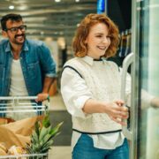 Couple shopping for groceries, choosing frozen food in supermarket refrigerator